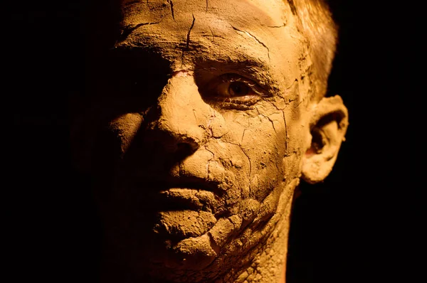 Yüz portre portre siyah arka plan üzerine. Kurutulmuş Kil yüzünde, kırık cilt. Yüzünde boş ekran.