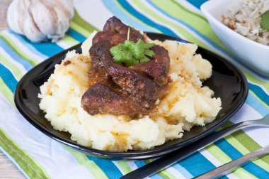 Kavrulmuş domuz eti boyun kişniş yaprağı ve taze sebze salatası ve arka planda Çiğ sarımsak ile dekore edilmiş patates ile