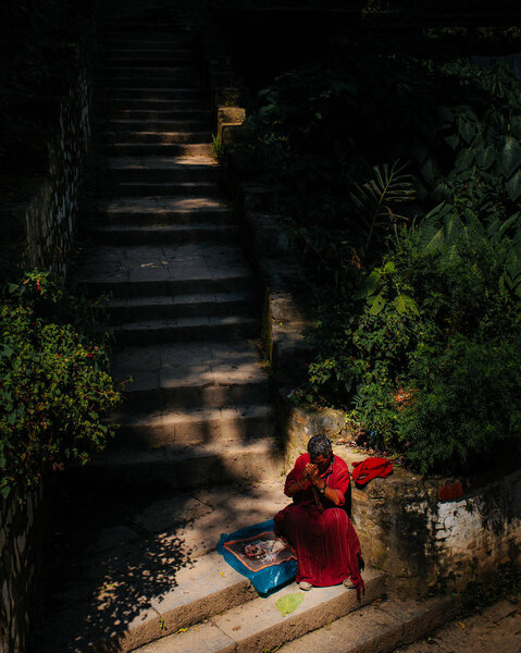 человек в одежде, сидящий у лестницы при солнечном свете
