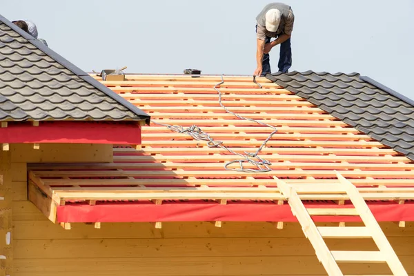 Workers build a roof on the house.,