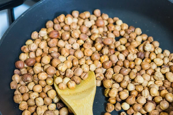 fry hazelnuts in a frying pan. fresh nuts in the pan.