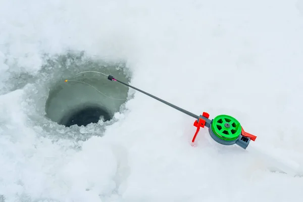 Winter fishing. Winter fishing rod next to the hole in the ice