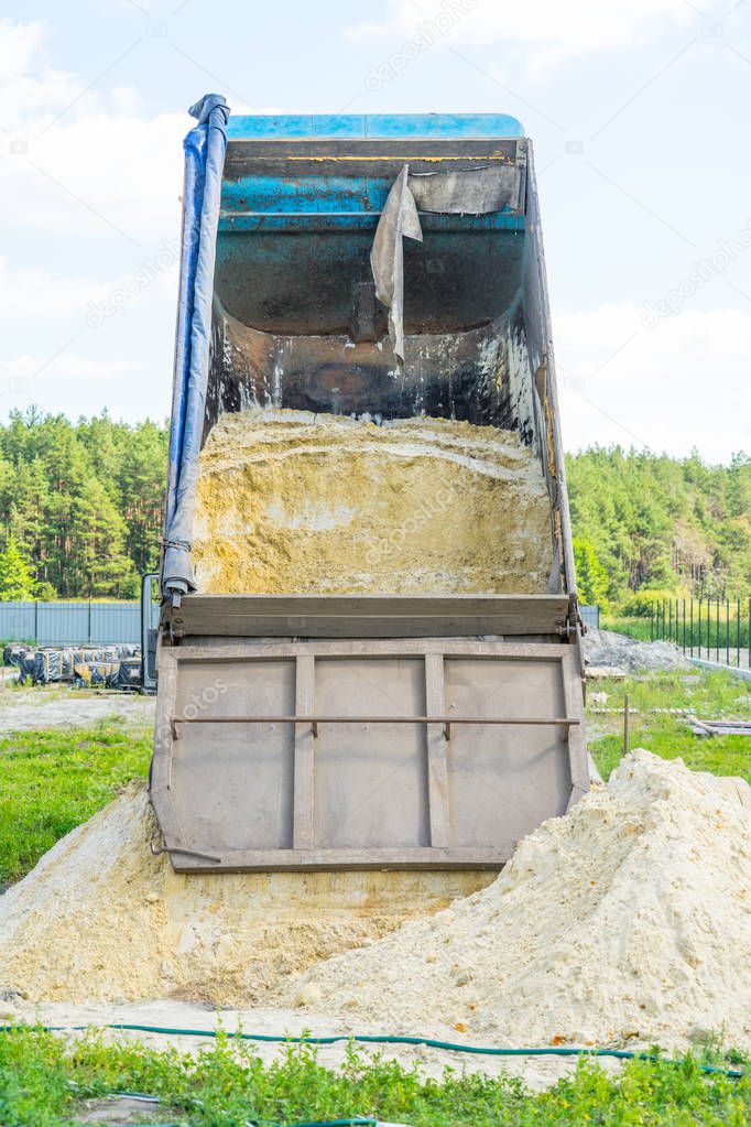 Delivery of sand for construction. dump truck unloads the sand. Place for your text