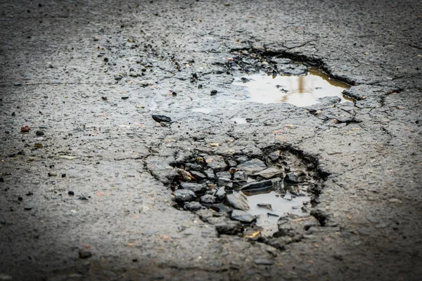 The hole in the road. Asphalt with defects. Dangerous encounter on the road.