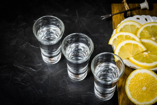 Forte alcol versato in un bicchiere. affettatura limone . — Foto Stock