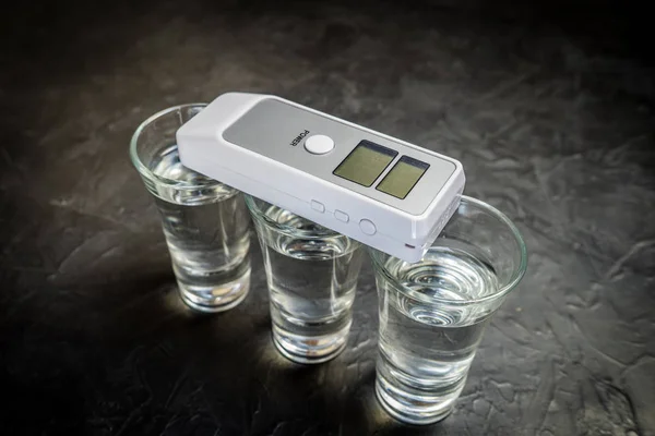 Breathalyzer and alcohol in a glass. photo on a dark background. — Stock Photo, Image