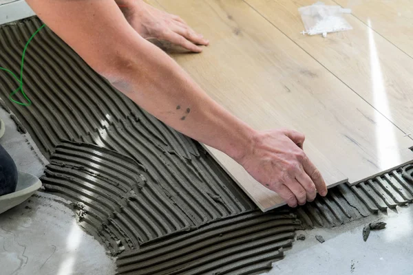 Laying tiles on the floor with a special glue.