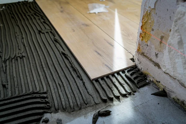 Laying tiles on the floor with a special glue.