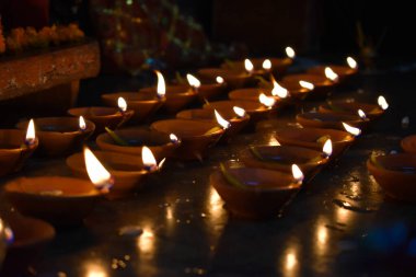 Geleneksel toprak lambaları, Diwali festivali vesilesiyle renkli rangoli (toz) tasarımları ile güzel bir desen içinde dizilmiş.