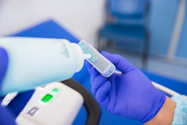Ultrason tanı doktoru sensörü tutuyor ve jeli uyguluyor.