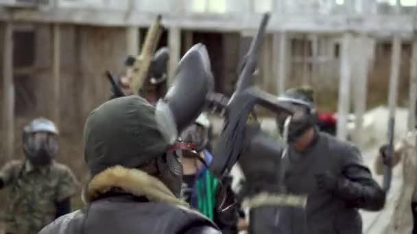 Толпа людей в маске для пейнтбола поднять оружие поближе, начать фанатичный удар 4К . — стоковое видео