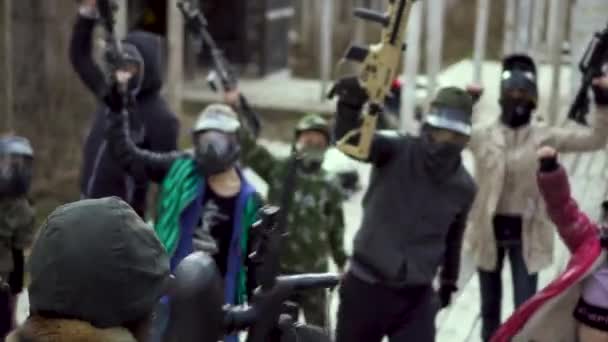 Many mans in paintball mask lift up closeup gun, begin aggressive 4K strike. — Stock Video