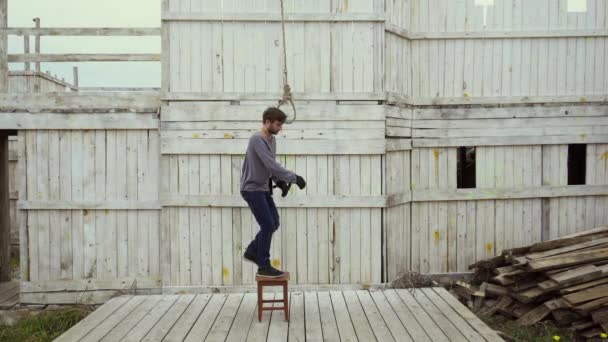 Человек устал в жизни крупным планом встать стул на виселицу, прыгать с петлей вокруг шеи — стоковое видео