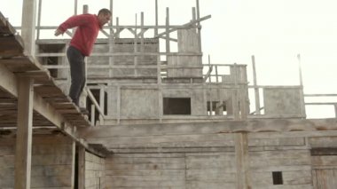 Man parkour on street doing frontflip jump from great height of wall. Front flip