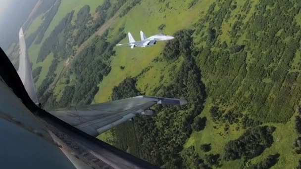 Aviões voam sobre o campo de batalha e um jato tenta derrubar o outro fazendo loop . — Vídeo de Stock