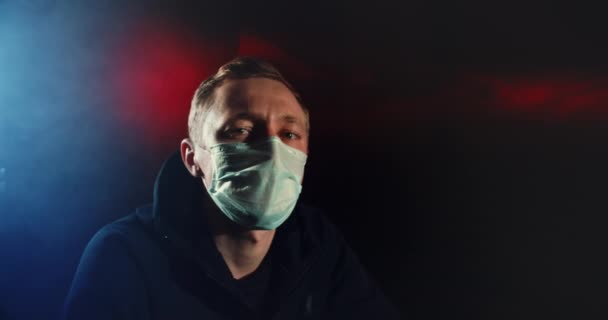Портрет в маске человека, смотрящего на огни камеры. Коронный вирус covid-19 4K . — стоковое видео