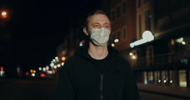 Человек в маске ходить ночью улица города среди огней рынка коронавируса ковид-19 4K . — стоковое видео