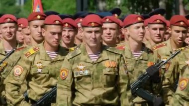 Yürüyüş subayları kırmızı bereli tüfek Kalaşnikov AK 47 yakın plan 4K.