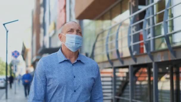 Senioren gehen durch leere Straßen. Alter Mann setzte Covid-19 Maske auf. Coronavirus. — Stockvideo