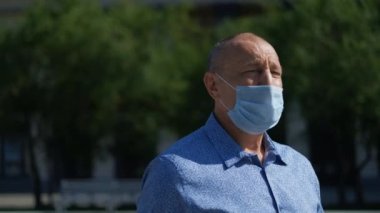 Maskeli yaşlı adam parkta yürüyor. Covid-19 burada, adam salgından korkmuyor..