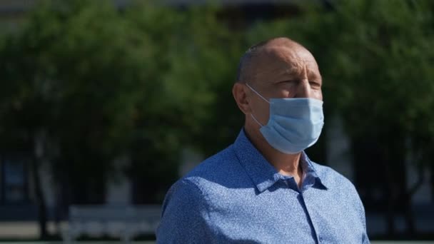 Oudere man met masker loopt in het park. Covid-19 is hier, de mens is niet bang voor een pandemie.. — Stockvideo