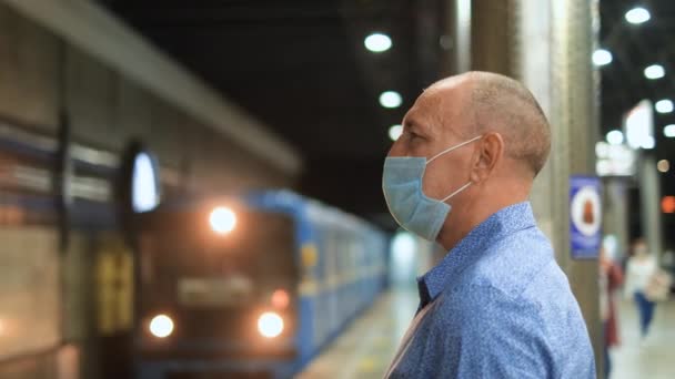 Masked old human wait train on platform of empty undergroung station. Covid 19. — Stock Video