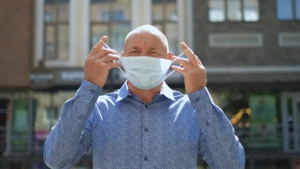 Il vecchio in pensione mostra come mettere la maschera durante l'epidemia di coronavirus. Covid-19 — Video Stock