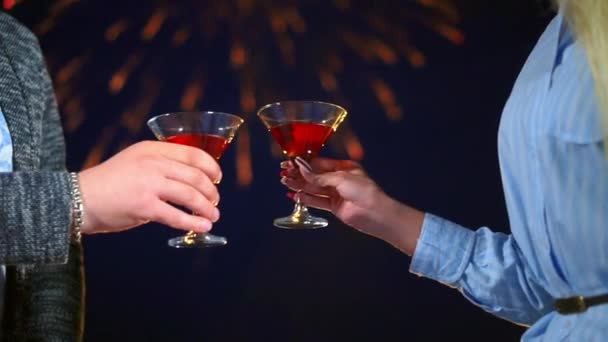 Paar liefdevolle kloppen glazen wijn closeup op achtergrond vuurwerk in nacht datum — Stockvideo