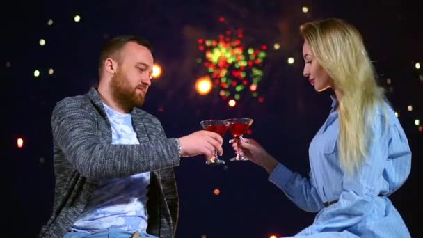 Feliz pareja amante de golpear vasos de vino en el fondo fuegos artificiales en la noche fecha. — Vídeo de stock