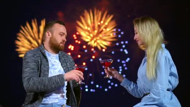 Twee liefdevolle mensen vieren klop glazen wijn op date met kleurrijk vuurwerk. — Stockvideo