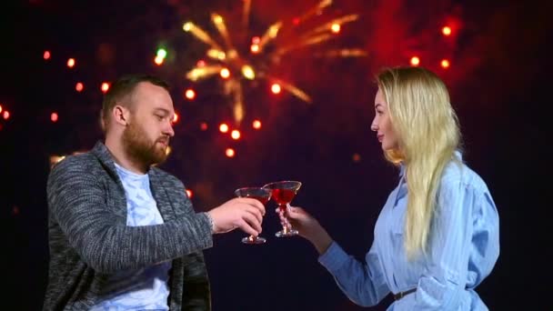 Feliz pareja amante de golpear vasos de vino en el fondo fuegos artificiales en la noche fecha. — Vídeos de Stock