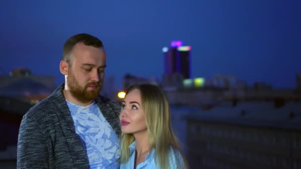 Влюбленная пара, глядя лицом к лицу, наслаждается освещением ночного города красивых свиданий в 4K. — стоковое видео