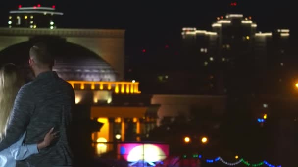 Пара любящие на свидании глядя яркое освещение театра ночью город задний вид 4K. — стоковое видео