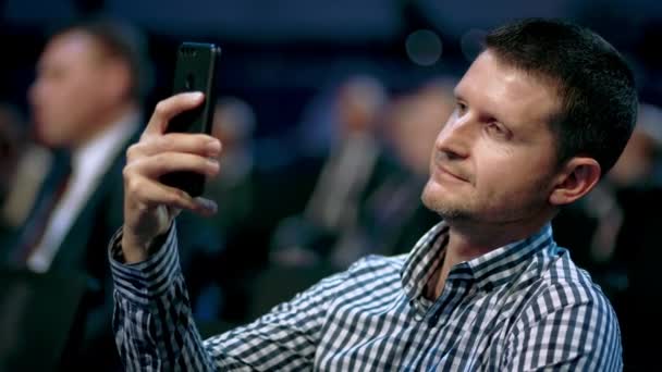 Persona tomando el teléfono de fotografía. Hombre de negocios escuchar conferencia en la audiencia multitud. — Vídeo de stock