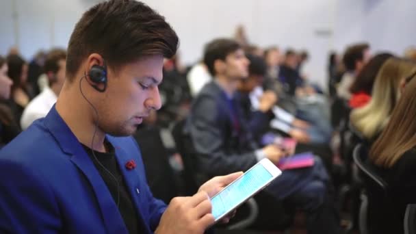 Estudante lotado público digitando tablet texto palestra faculdade. Homem use touch pad. — Vídeo de Stock