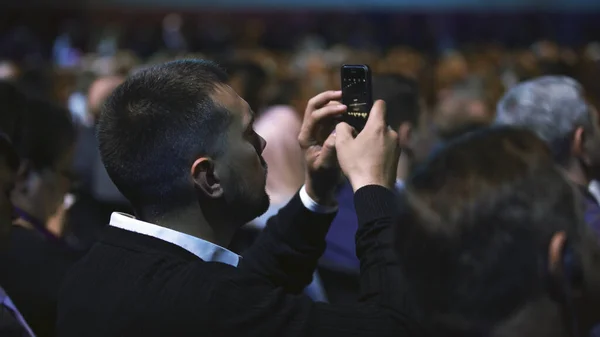 視聴者の電話撮影セミナー。講堂ビジネスの男性写真を撮る. — ストック写真