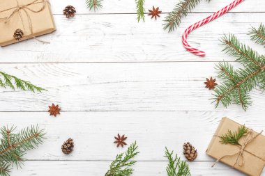 Yeni yıl hediyeleri ladin dalları ve beyaz ahşap arka plan tepe üzerindeki koni yakınlarındaki el sanatları kağıdına sarılı.