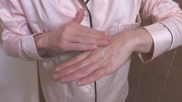 手にクリームを適用するパジャマの女性 — ストック動画