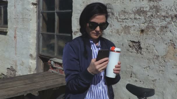 女性がスマート フォンを使用してコーヒーを飲む — ストック動画