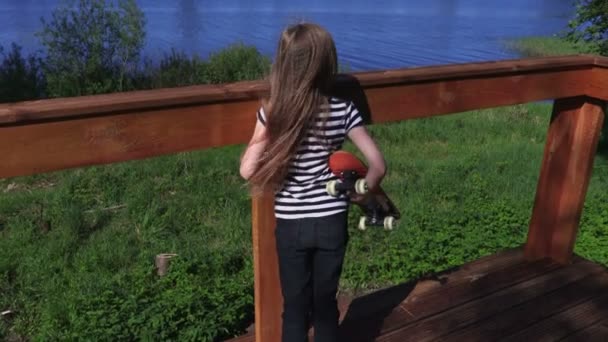 屋外でスケート ボードを持つ少女 — ストック動画