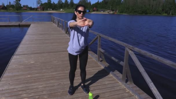 湖の近くの公園で運動する前にウォーム アップの女性 — ストック動画