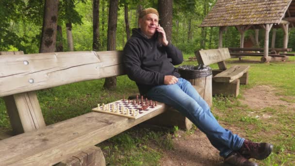 Homem Sentado Perto Tabuleiro Xadrez Falando Smartphone — Vídeo de Stock