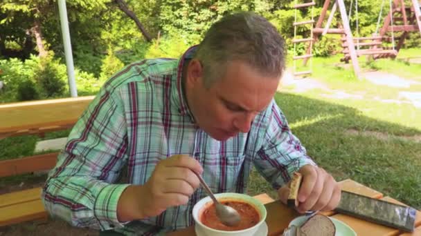 男が夏の屋外カフェでスープを食べる — ストック動画