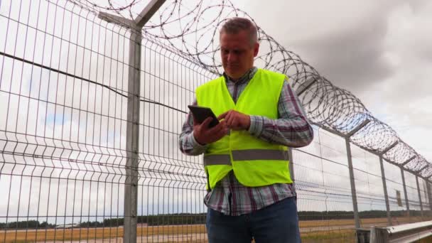 Чоловік Використовує Планшетний Біля Паркану Похмурий День — стокове відео