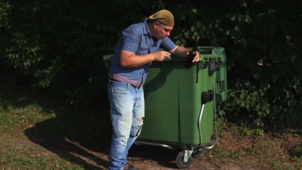 醉酒的无家可归者吸烟在废物容器附近 — 图库视频影像