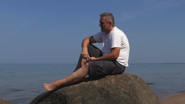 Mann Setzt Sich Ans Meer Auf Einen Felsen Und Entspannt — Stockvideo
