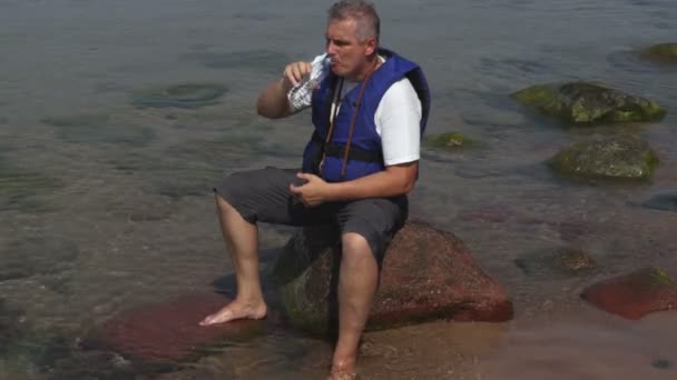 Man Een Zwemvest Drinkt Water — Stockvideo