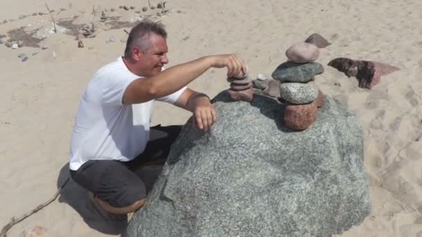 Man Bouwt Een Evenwichtige Stenen Piramide Het Strand Zomerdag — Stockvideo