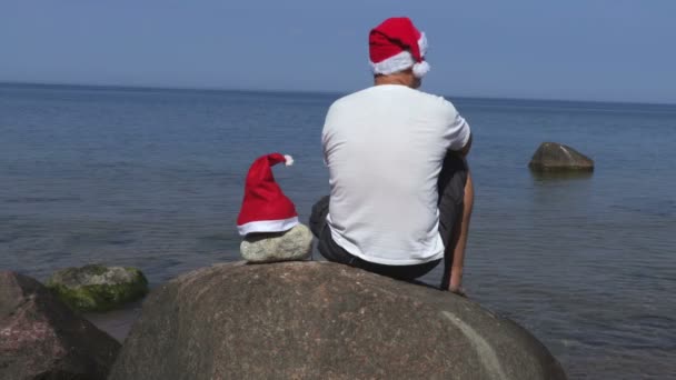 Homem Com Chapéu Papai Noel Pedra Perto Mar — Vídeo de Stock