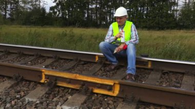 Demiryolu demiryolu parça üzerinde oturur ve kahve içer